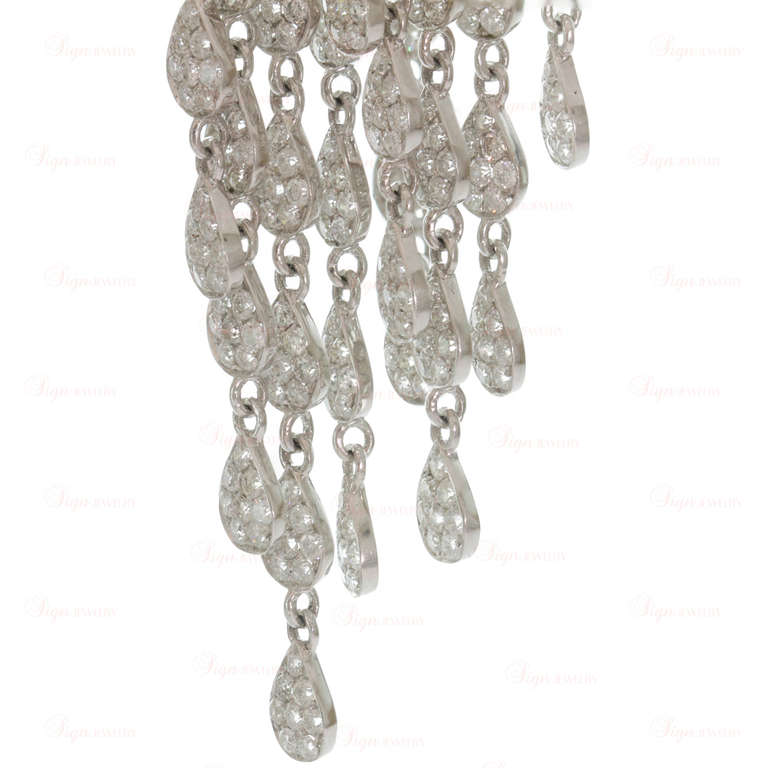 These gorgeous chandelier earrings are made in 18k white gold and feature dangling teardrop-shaped links beautifully set with sparkling round diamonds and suspended on two-row open hoops pave-set with diamonds. Chic and elegant. Measurements: 0.98