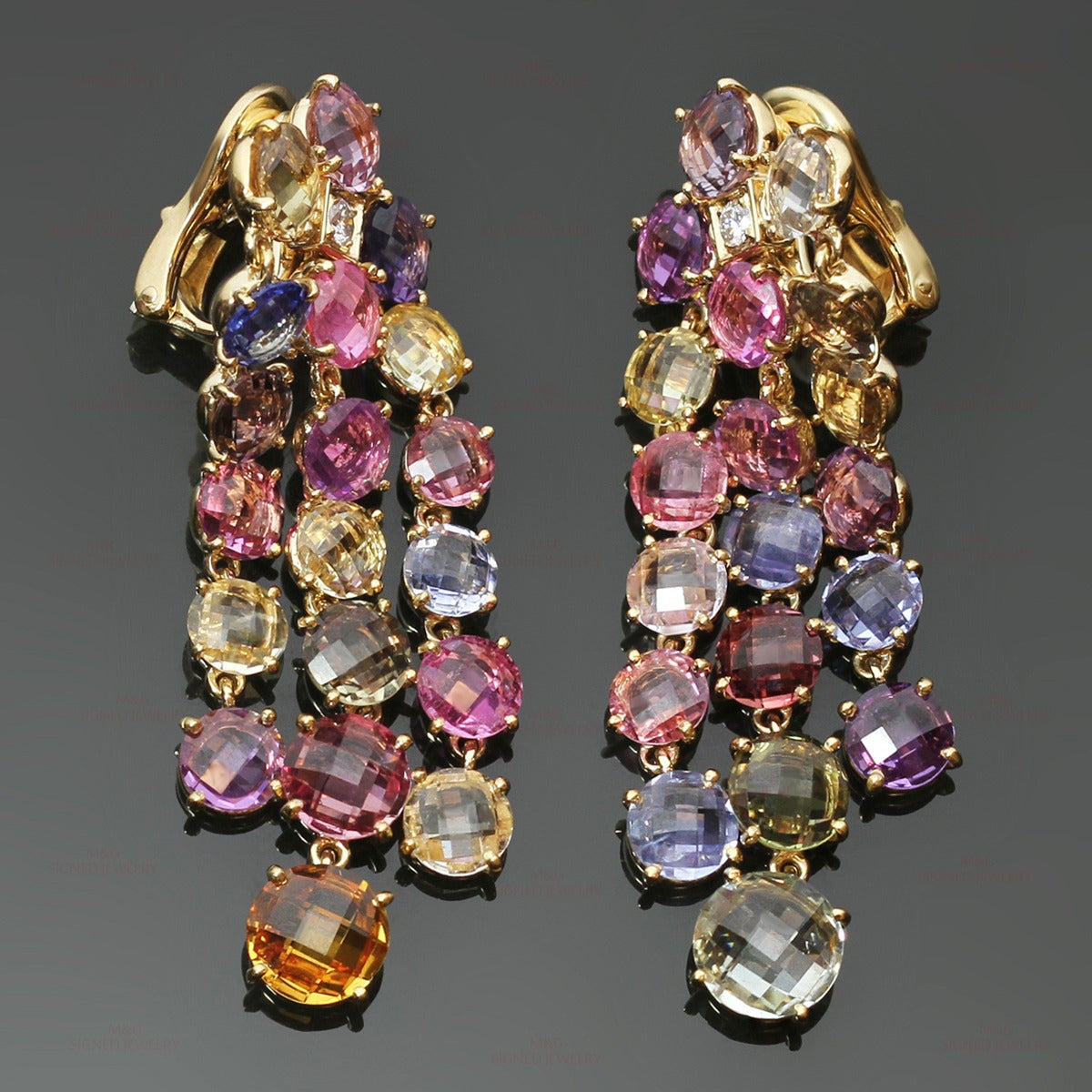 These rare Bulgari dangling earrings are made in 18k yellow gold and prong-set with colorful round faceted sapphires in yellow, orange, pink, blue, green and brown tints, accented with round sparkling diamonds of an estimated 0.12 carats. Earrings