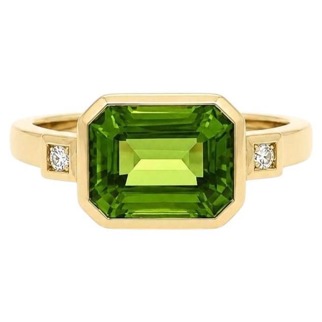 Anillo «East West» de oro amarillo de 14k con peridoto de talla esmeralda y diamantes en el bisel en venta