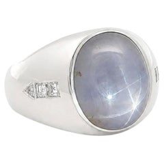 Anello con zaffiro a stella ovale in cabochon in oro bianco, con castone e fianchi decorati con un motivo a freccia in diamanti