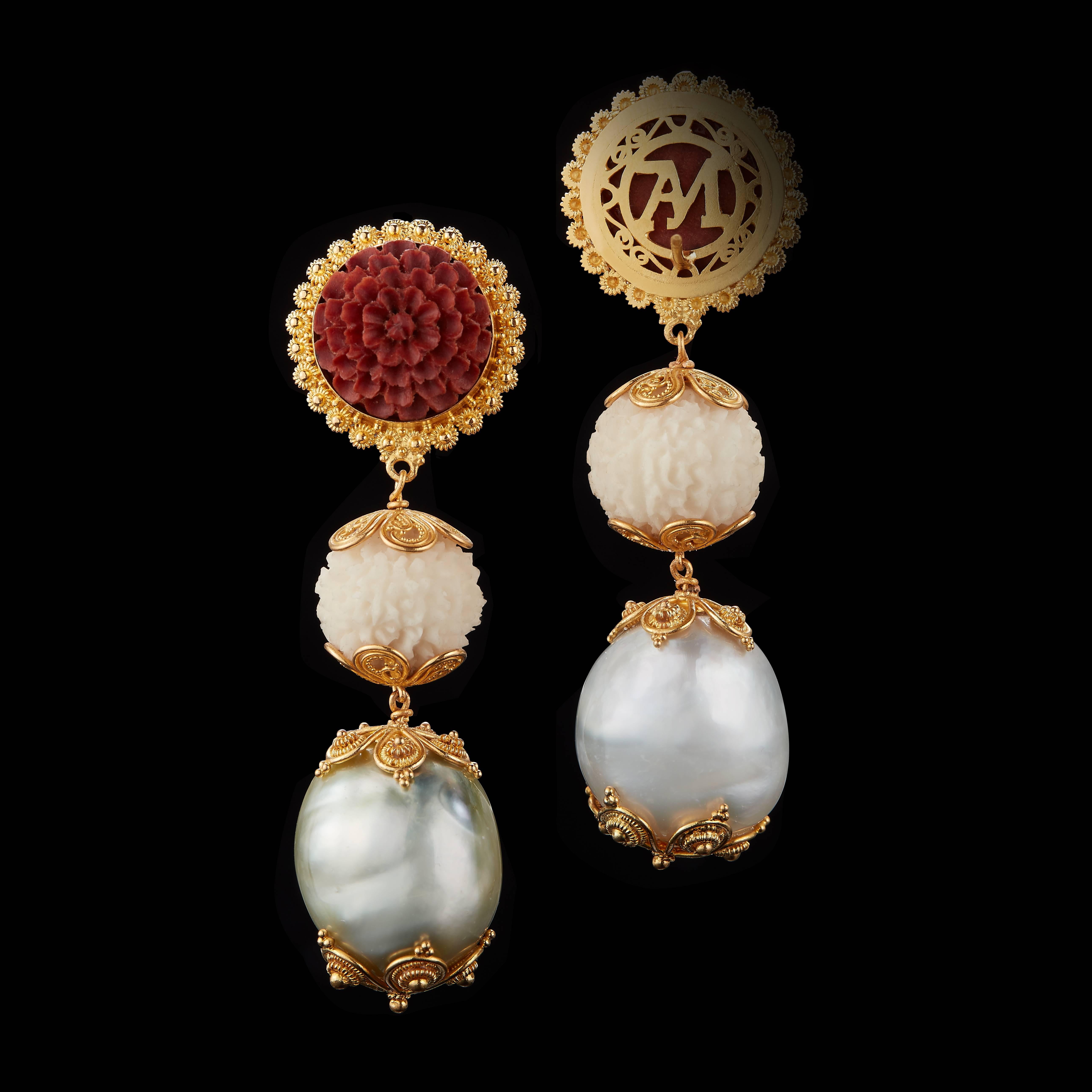 This pair of three-tier earrings feature intricately carved 14.65mm Sawo wood flowers, wild-harvested Tagua seed Rudrakshas and grey-white Baroque Pearls. Accented by prolific 22 karat yellow gold hand carvings, these limited edition
earrings are