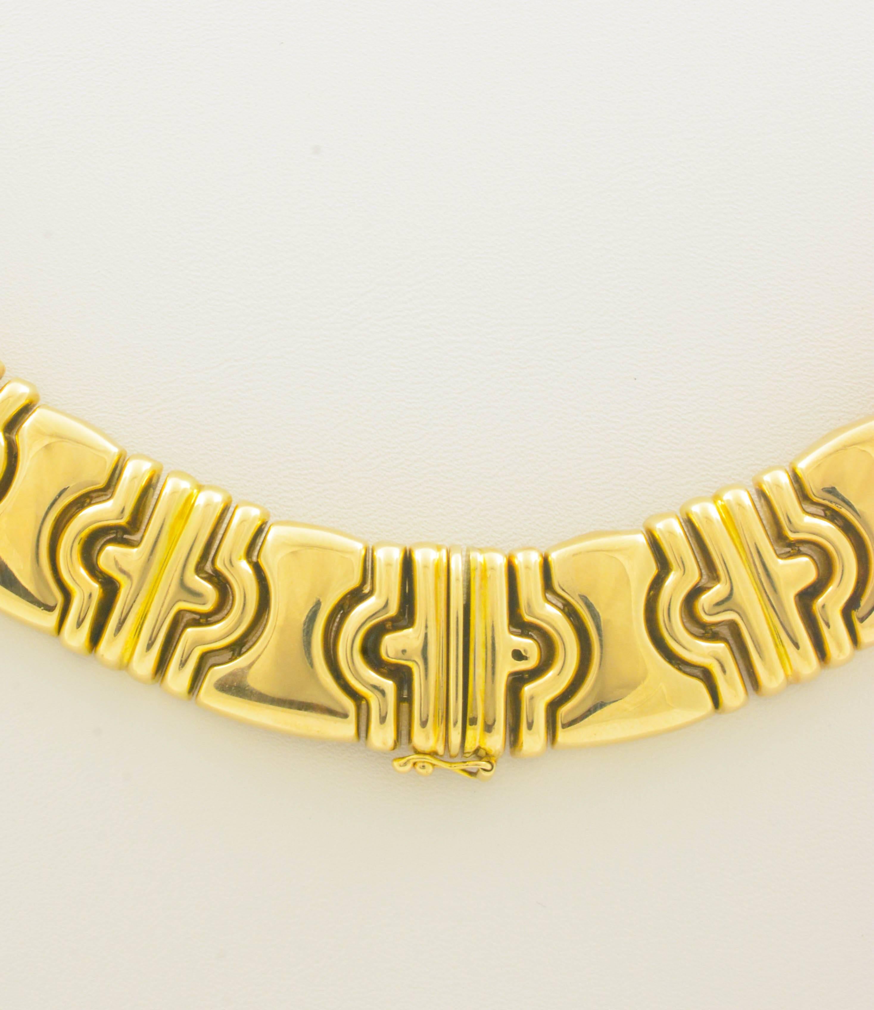 This 14kt yellow gold collar necklace is fashioned in stunning Byzantine style. Measuring 17in long and 3/4in wide, it draws the eye by alternating wide high polished links with sections of three smaller domed links. The total weight of this