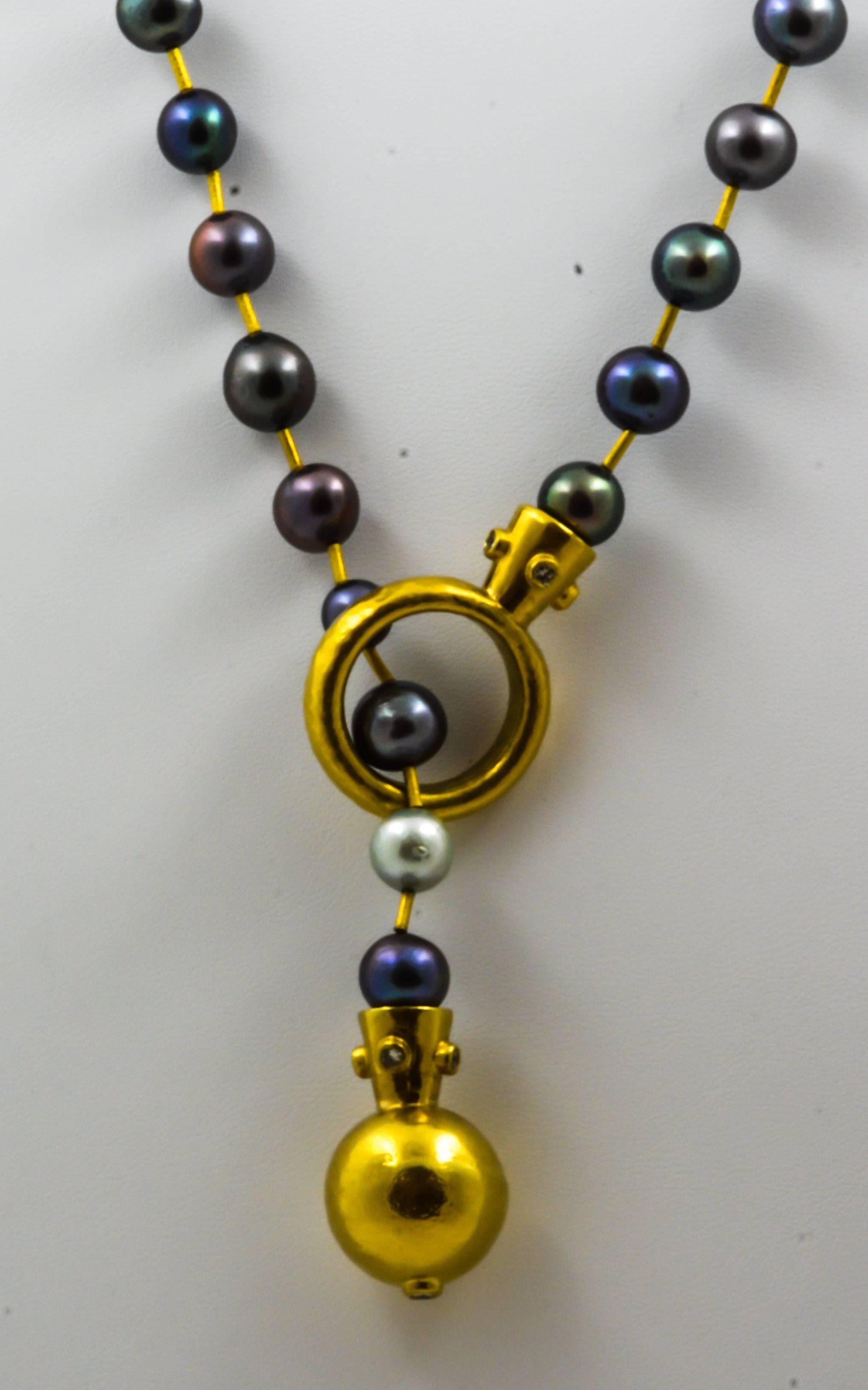 Varied pastel black pearls are strung with 22kt yellow gold, textured, tube beads in this extraordinary necklace. Featuring a Lariat style circle with a 22kt gold ball and diamond end as the clasping mechanism, the necklace is set with nine round,