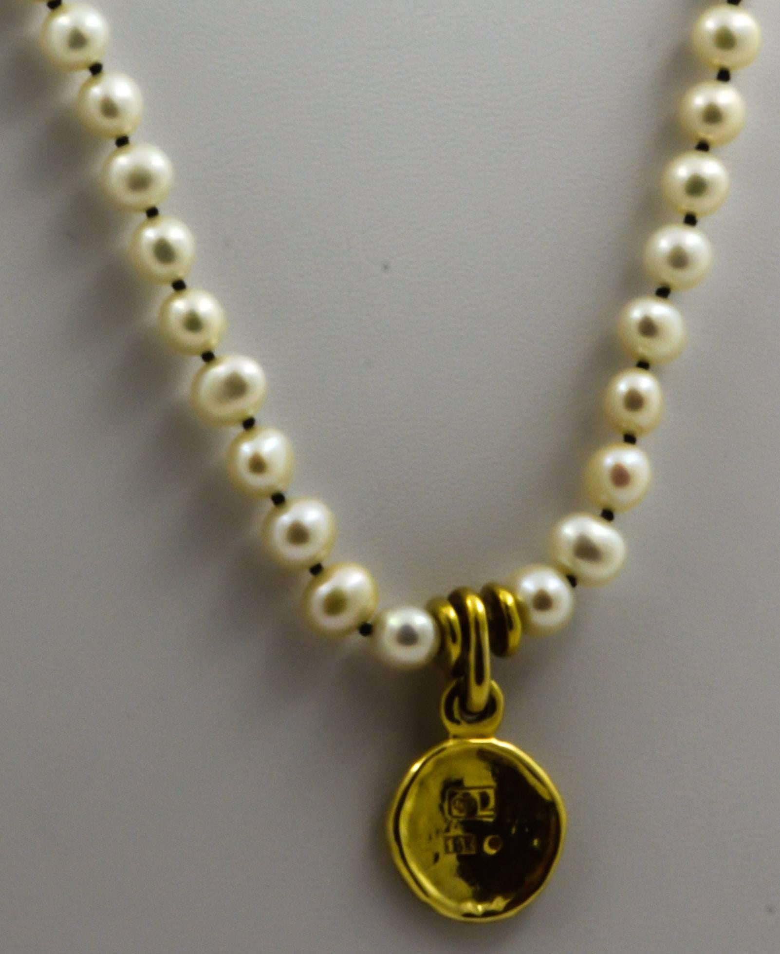 A gold coin with a rustic design is attractively displayed on a 32in tapered strand of cultured freshwater pearls in this unique pendant. Tapering from 6.86mm at the pendant to 3.65mm at the clasp, the pearls are strung on a contrasting black cord