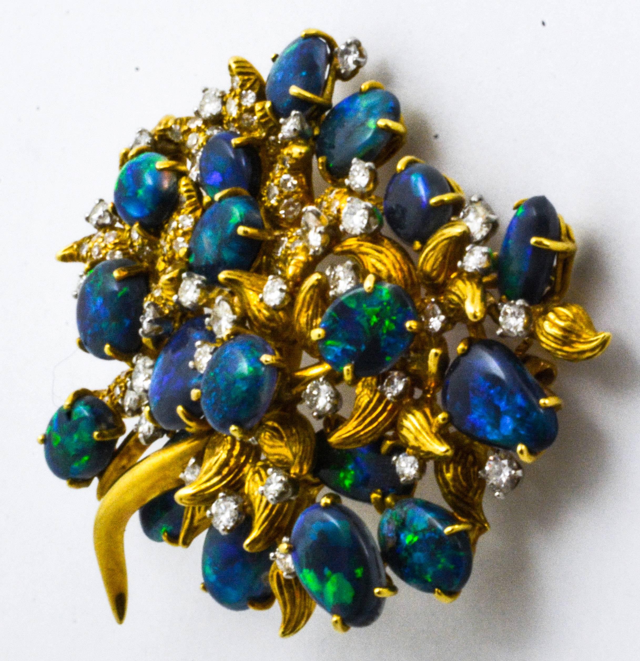 Julius Cohen designed this beautiful brooch to capture the imagination by featuring cabochon cut black opals of exquisite quality,  These opals play the light with beautiful blues and bright flashes of green.  Contrasting and accenting these