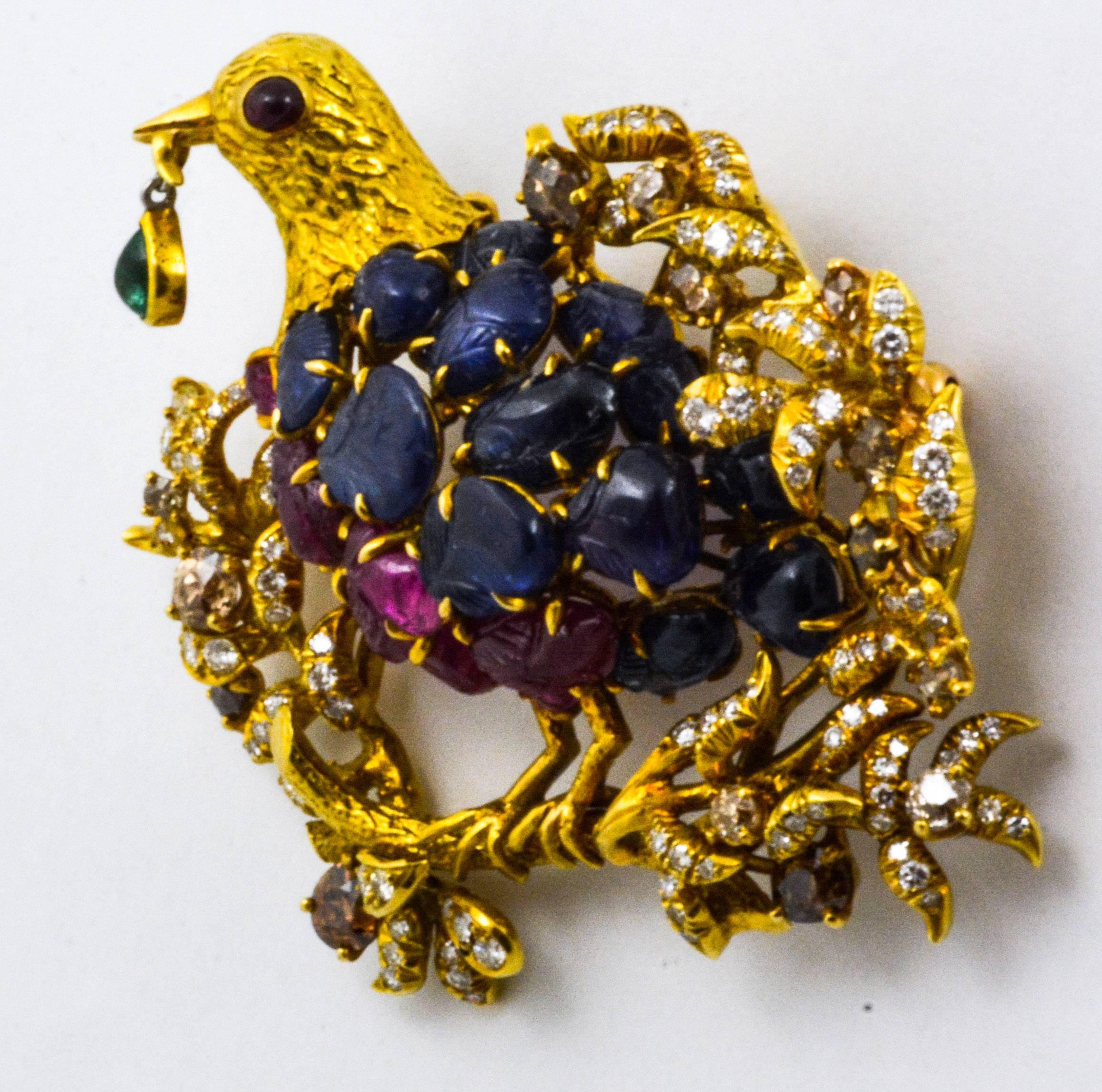 Julius Cohen crafted this brooch from 18kt yellow gold to look amazingly like and actual bird on a limb.  The body of this adorable little bird is set with carved blue sapphires and rubies.  Julius Cohen used round cabachon cut blue sapphires for