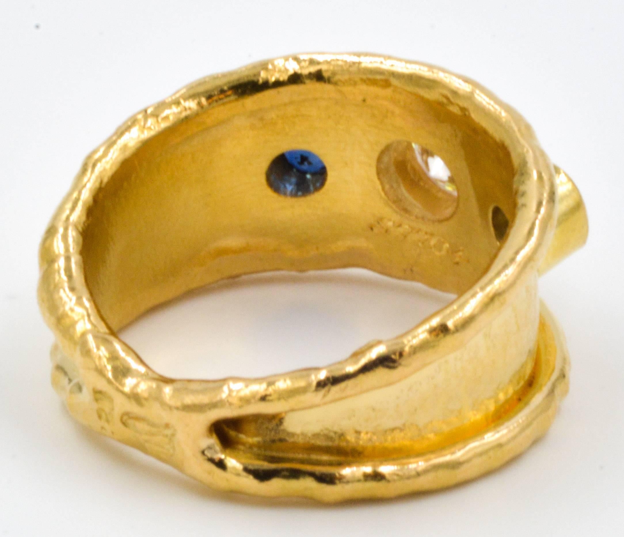 This classic Jean Mahie ring is handcraft in 22kt yellow gold and is centered by a bezel set round brilliant cut diamonds that weighs 0.66 carats and accented with two round brilliant cut blue sapphires that have combined weight of 0.35 carats. 