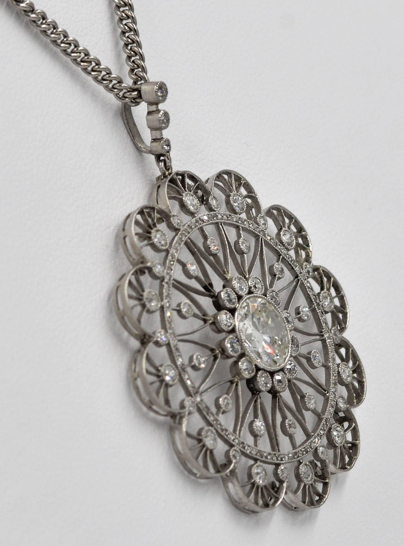 This platinum Edwardian pendant is a classic example of Edwardian design.  The pendant centers on a beautiful 1.75 carat round European cut diamond that is bezel set and surrounded by twelve Old Mine cut bezel set diamonds. Intricate lacy patterns