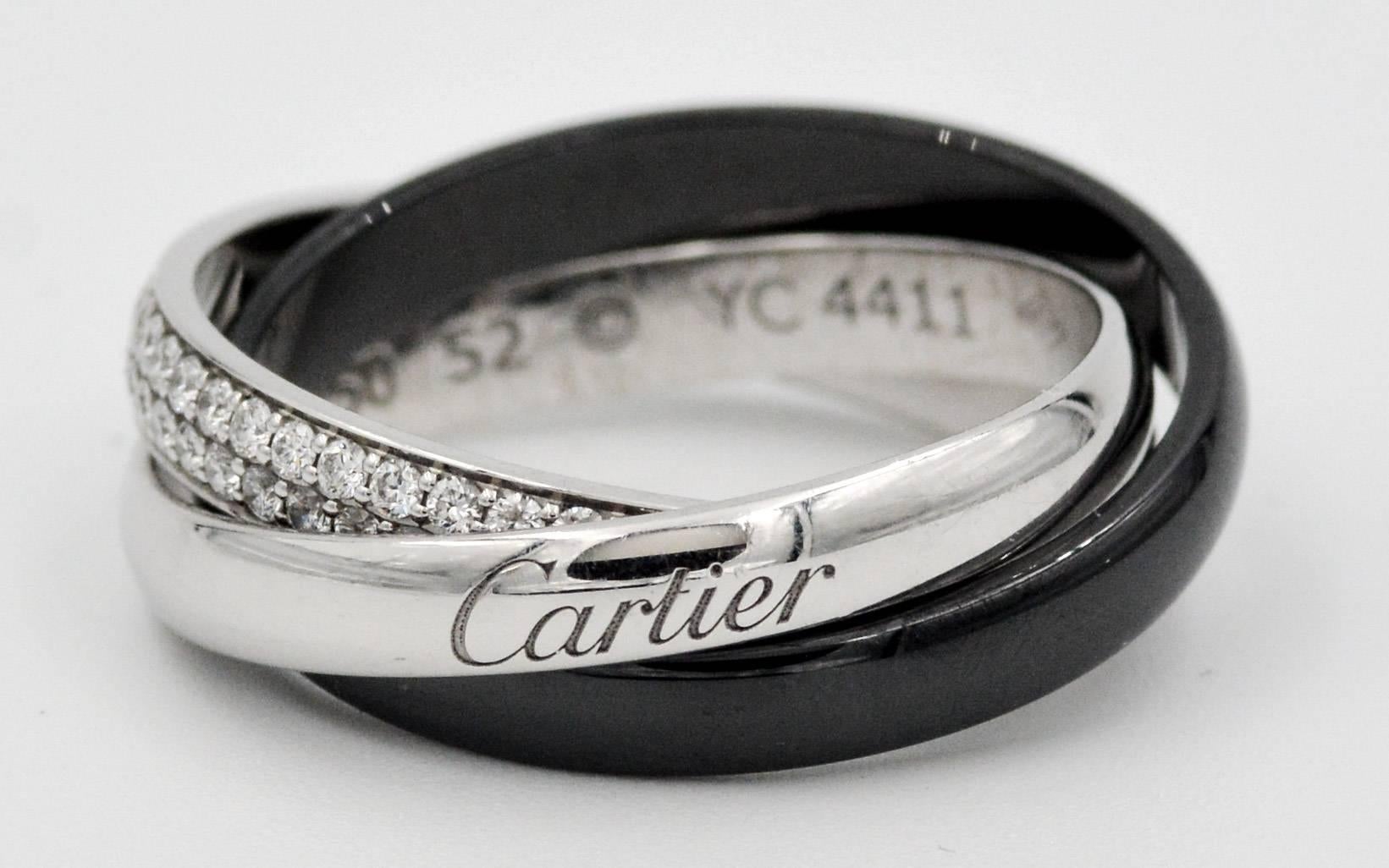 This classic Cartier Trinity rolling ring is made of of three contrasting domed bands.  One of the Cartier bands is a black ceramic domed band, another is 18kt white gold engraved "Cartier", and the other is 18kt white gold pave set with