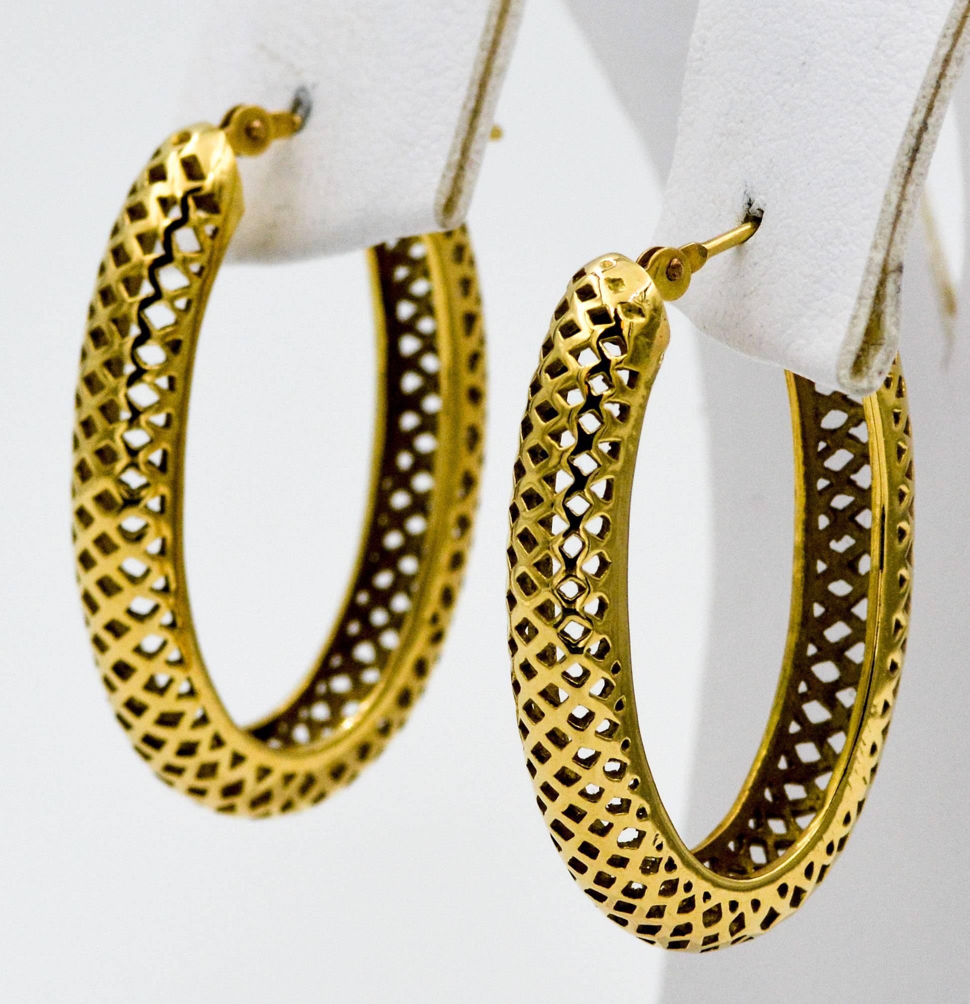 Experience the easy alternative to solid gold in these classic Ray Griffith hoop earrings. Executed in the Ray Griffith signature style of open crown worked hollow stock, these 18 karat yellow gold earrings are shaped into an elegant oval hoop that