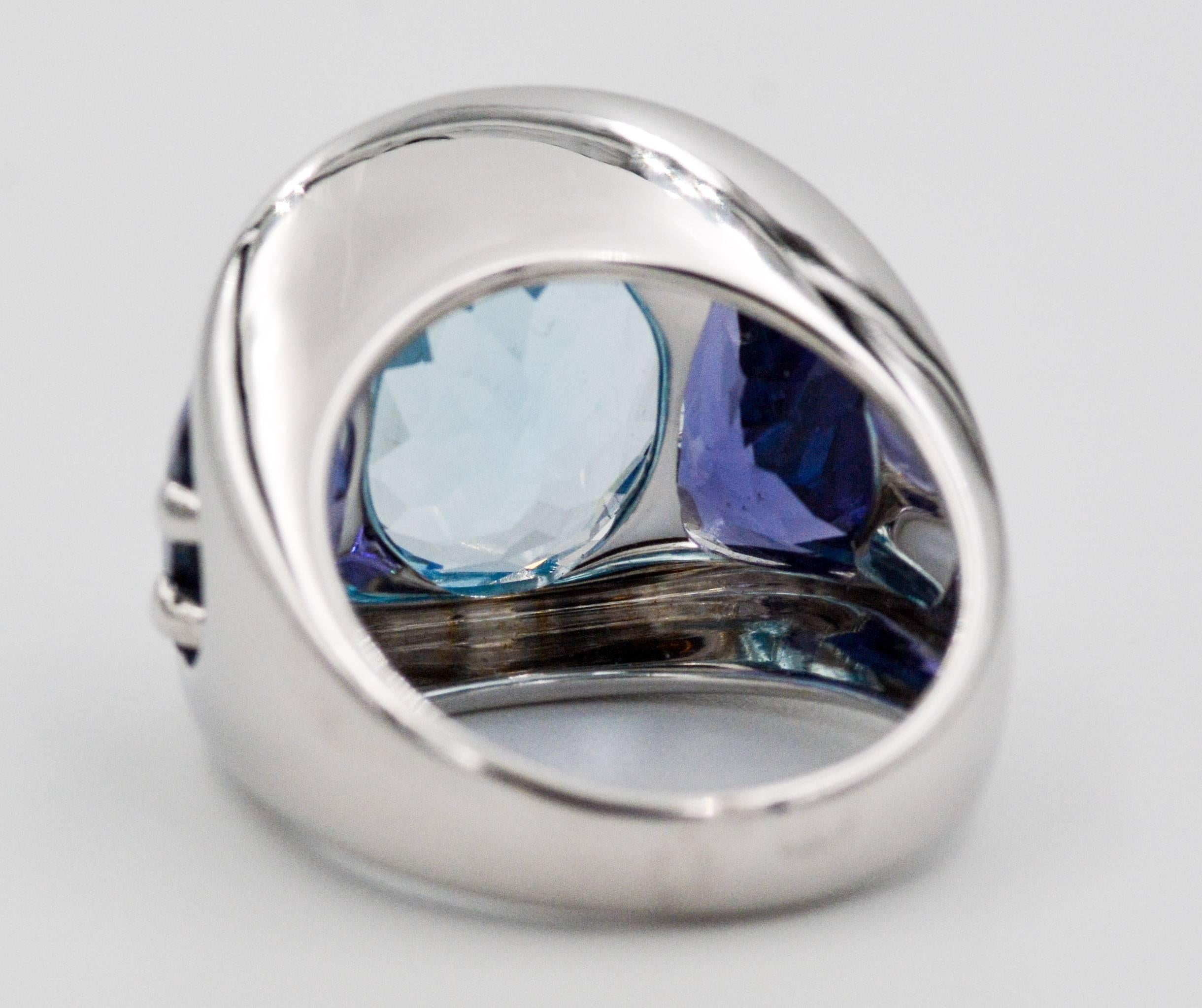 Seaman Schepps centered this amazing ring with an amazing oval faceted blue topaz that measures 15.22X12.00 mm.  Accenting and contrasting the rich blue of the oval topaz Seaman Schepps set two rich purple trapezoid cut iolite stones which measure
