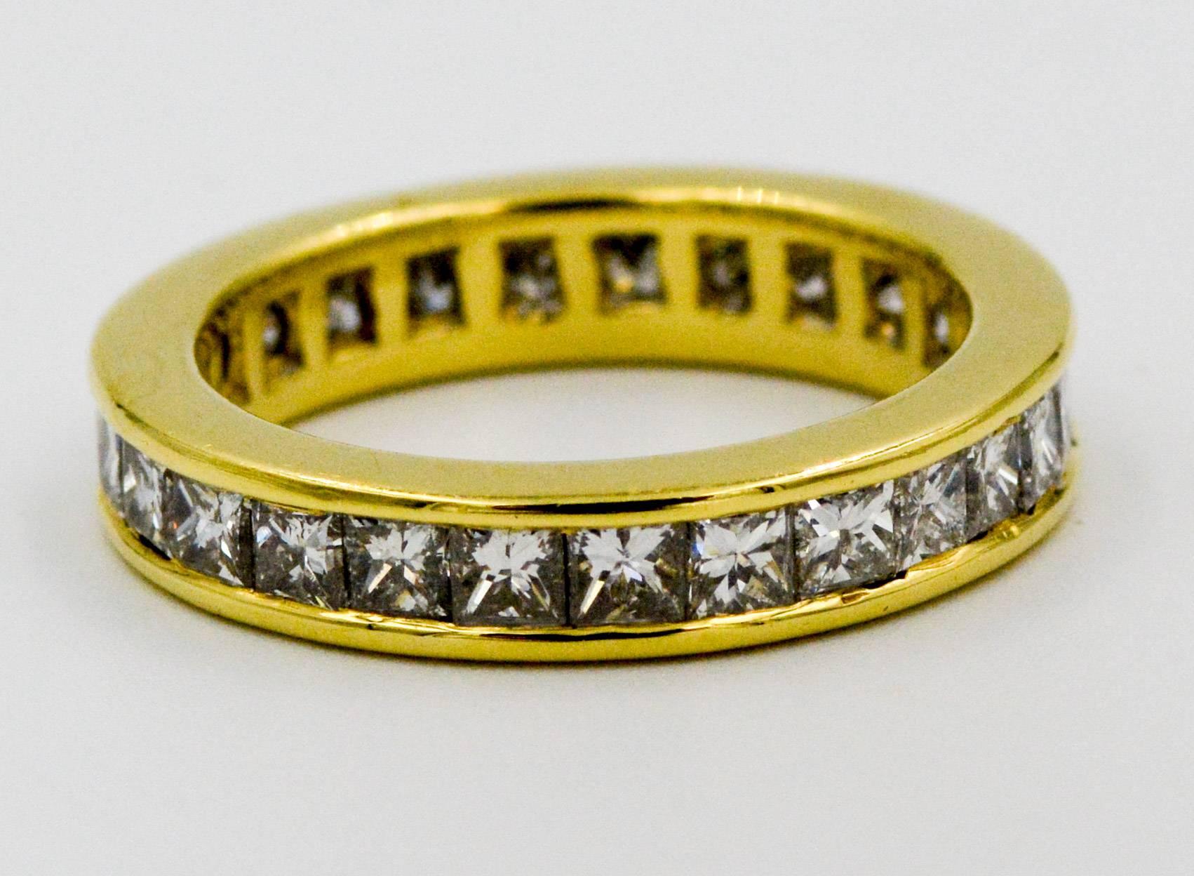 Princess cut diamonds sparkle in this eternity band ring crafted in 18 karat yellow gold. This eternity band features 2.00 carats of dazzling channel set princess cut diamonds, H color and SI1 clarity. Ring is a size 5.5. 