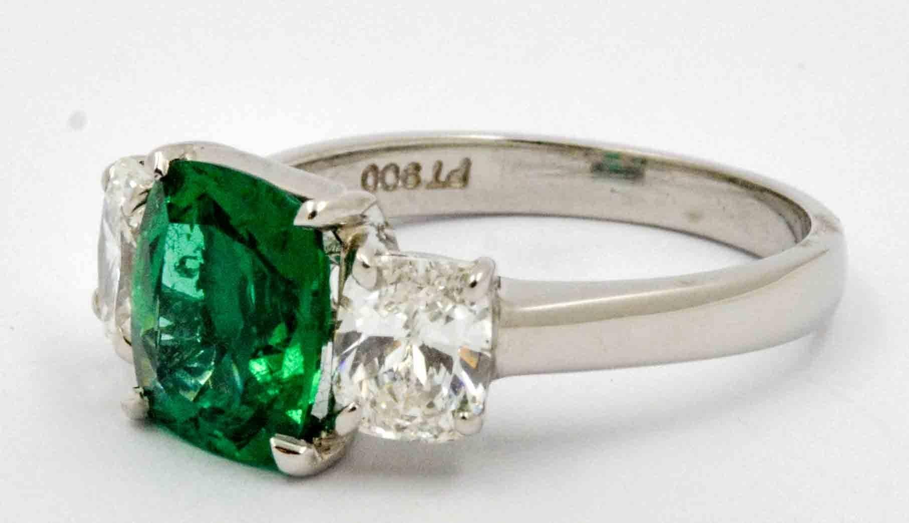 As green as the hills in Ireland, this rapturous platinum JB Star engagement ring is centered with a 1.80 carats vivid bright green cushion cut Emerald.  Accenting this amazingly bright green Emerald are two matching cushion cut diamonds that have a