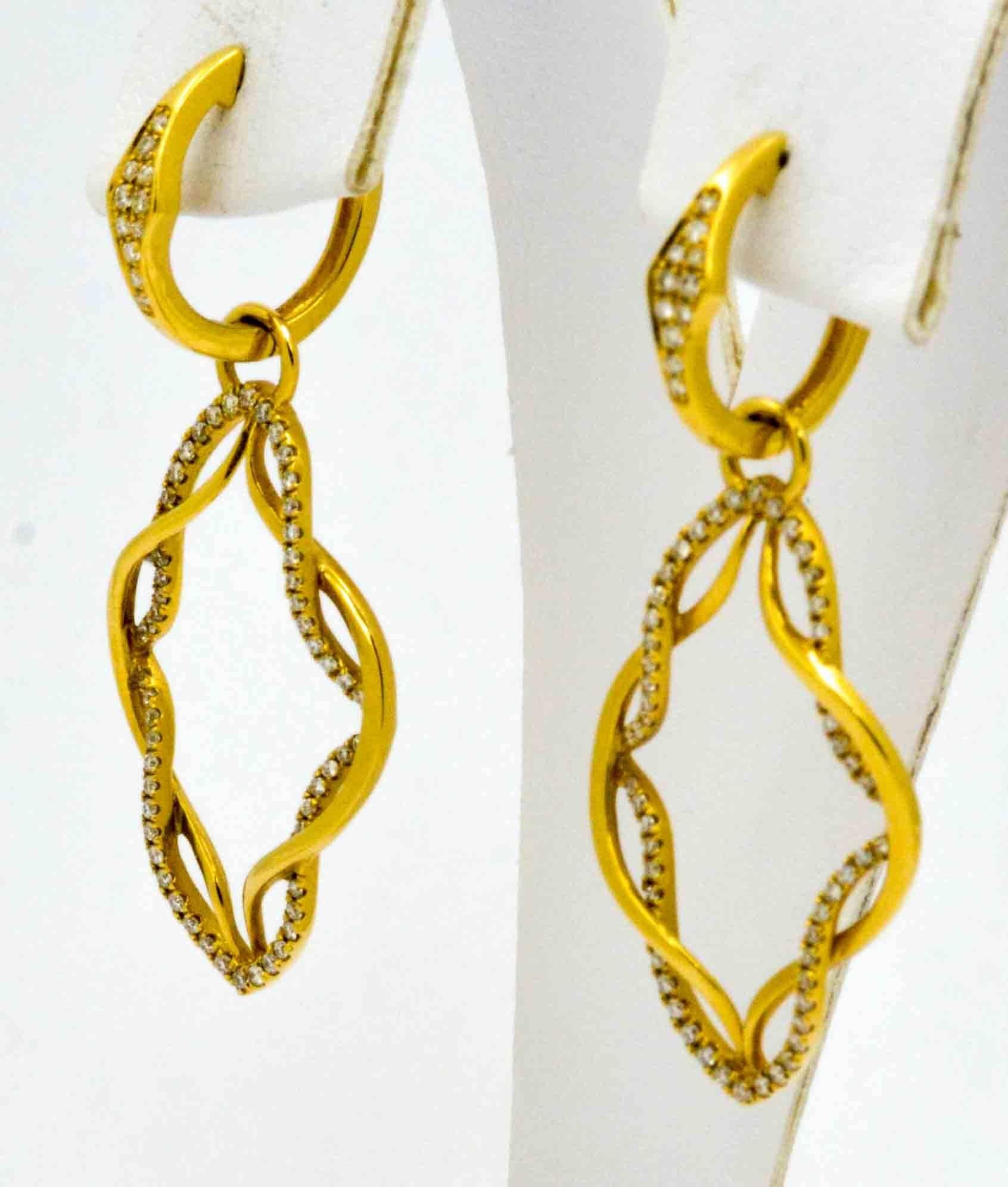 Dazzle your way from day to evening in these spectacular, light catching Katie Decker earrings crafted in a very attractive ribbon like frame suspended from a pair of hinged hoops.  The 18K yellow gold frame and earrings are set with round brilliant