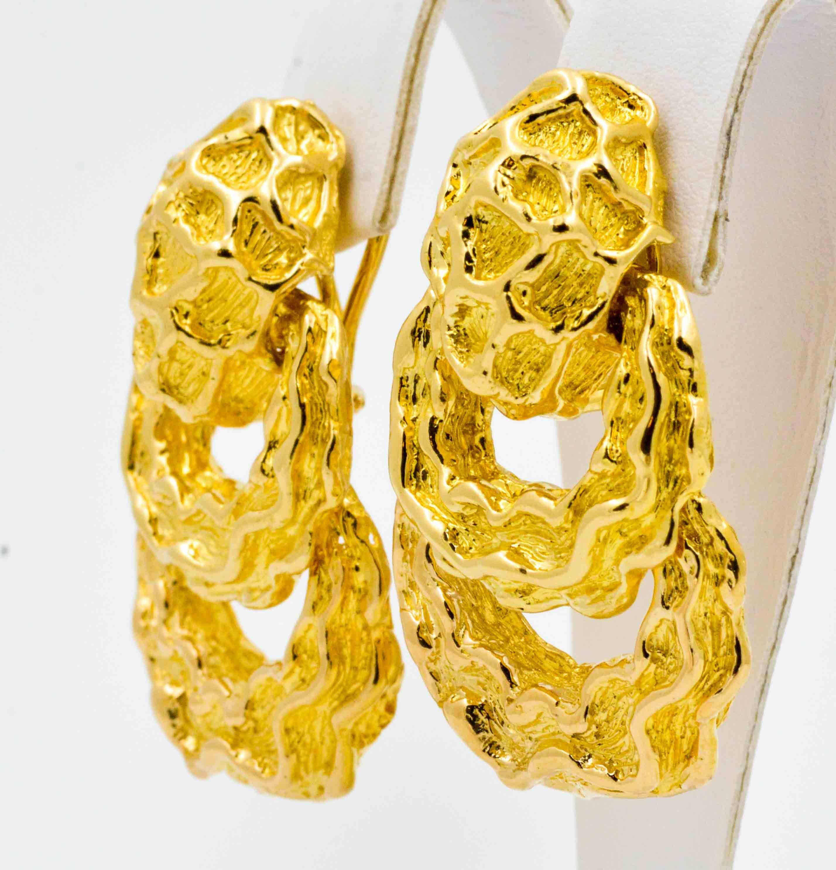 This adventurous pair of door knocker style earrings is crafted in bold 18kt yellow gold.  The door knocker earrings have a random pattern of free form texture that contrasts between a rough finish and a bright high polished finish.  The knocker
