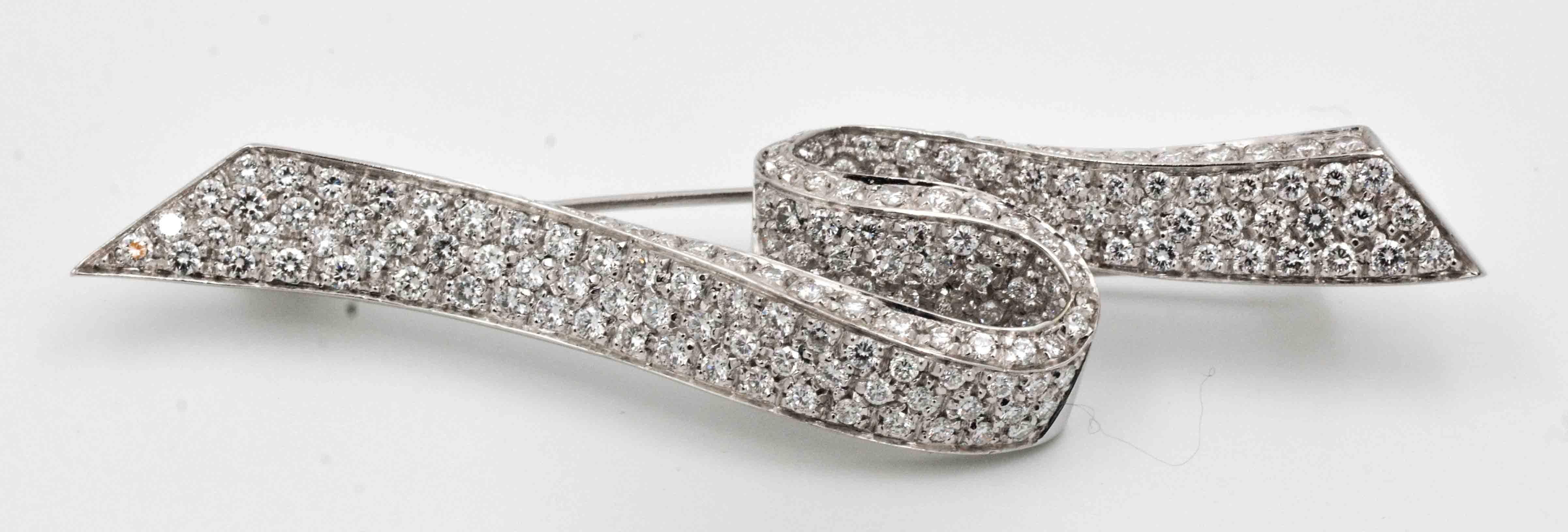 A glamorous ribbon pin crafted in platinum and 18kt white gold is pave set with a total of 2.31 carats of round brilliant cut diamonds (G-H color and VS clarity).  This stunning pin is held securely with a double stick pin on the back with an