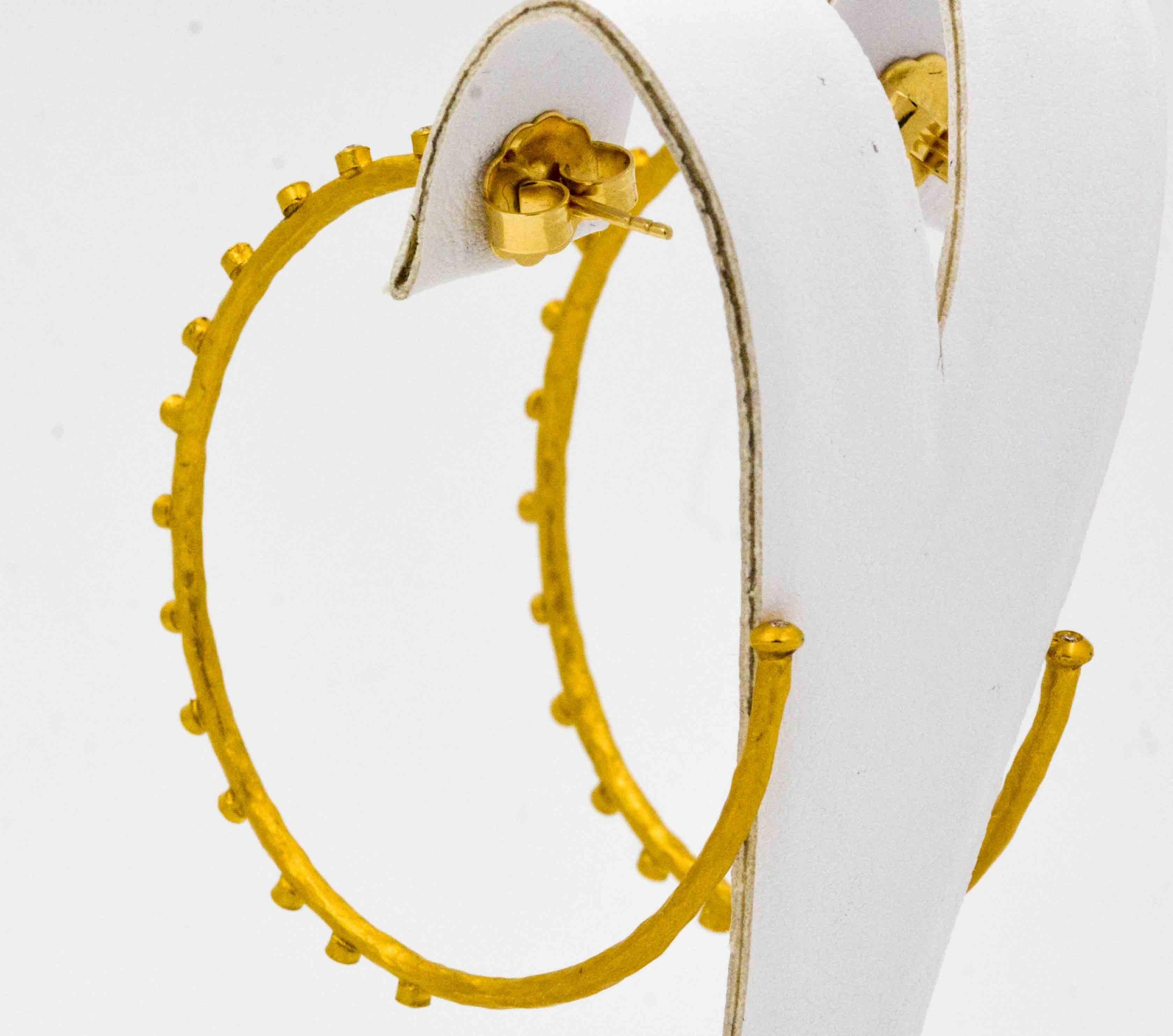 Scintillating sparkles of light come from 0.41 ctw diamonds bezel set on these 55 mm 24 karat yellow gold hoop earrings. She will never tire of wearing these extraordinary hoop earrings with 18 kt yellow gold posts and 22 kt yellow gold backings.