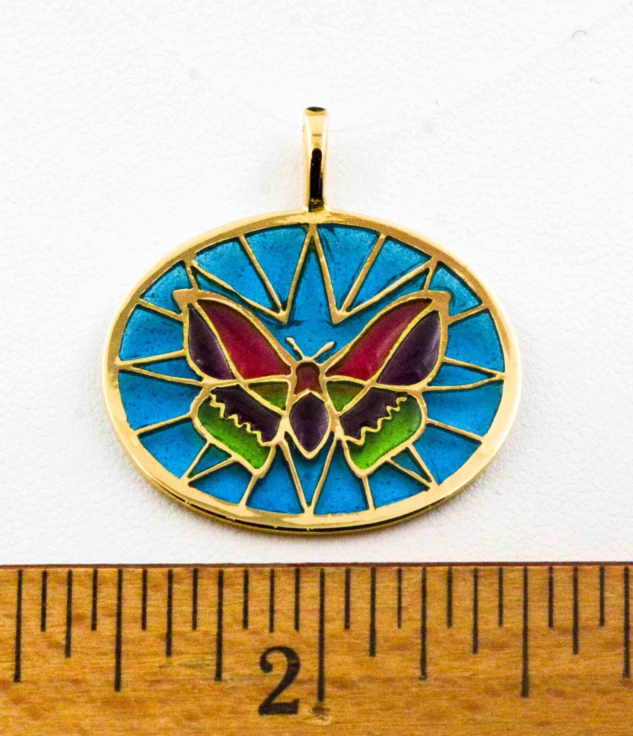 Bright red, green, and purple make up the body of this hand crafted Plique a Jour glass enameled butterfly. The beautiful background is a mesmerizing soft blue. The master craftsman created this delicate little pendant in the art of Plique a Jour