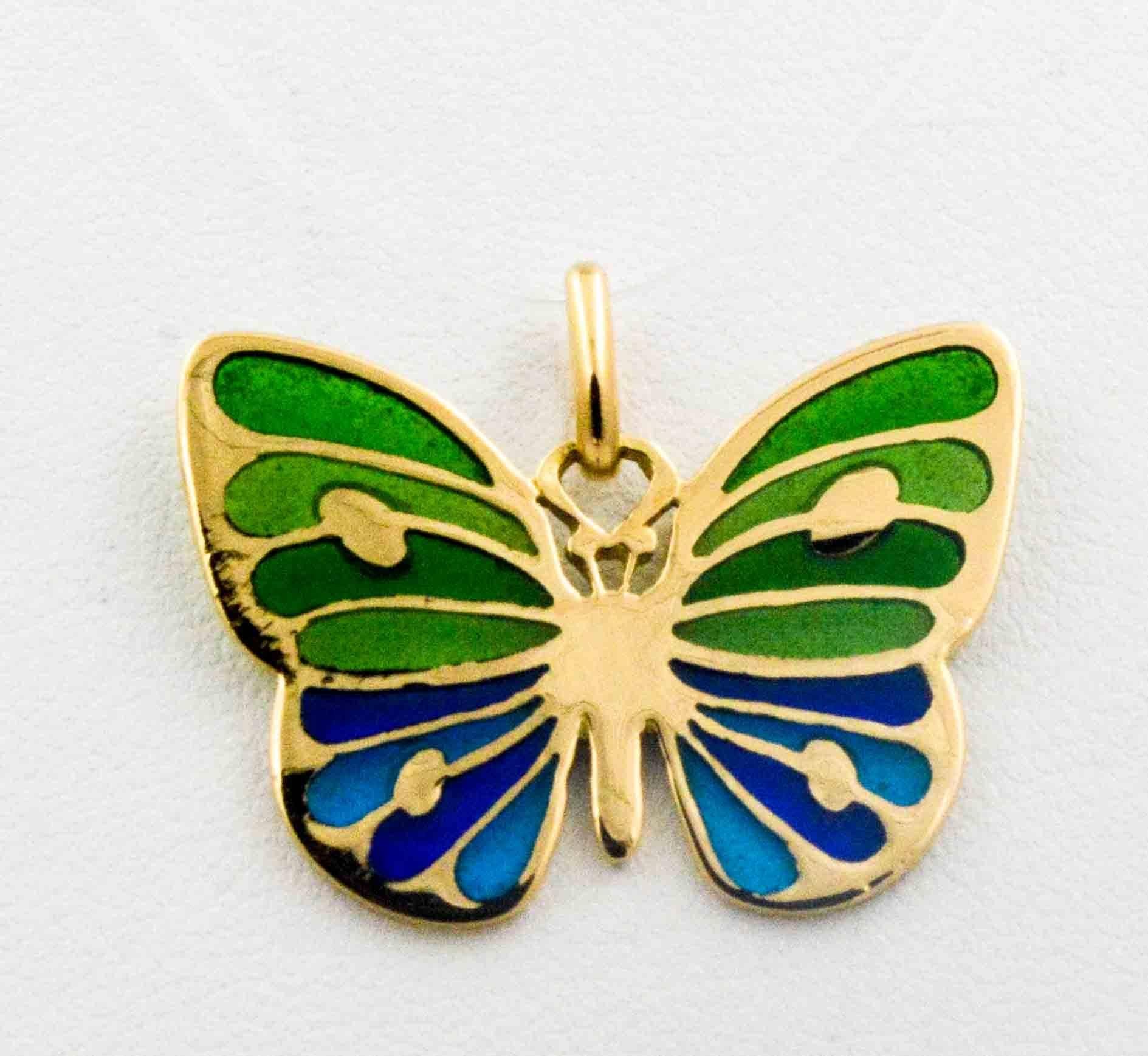 This charming little glass enameled butterfly, in hues of soft blues and greens, is hand crafted in the Plique a Jour art. 18 karat yellow gold accents the body and wings of this captivating delicate little butterfly. 