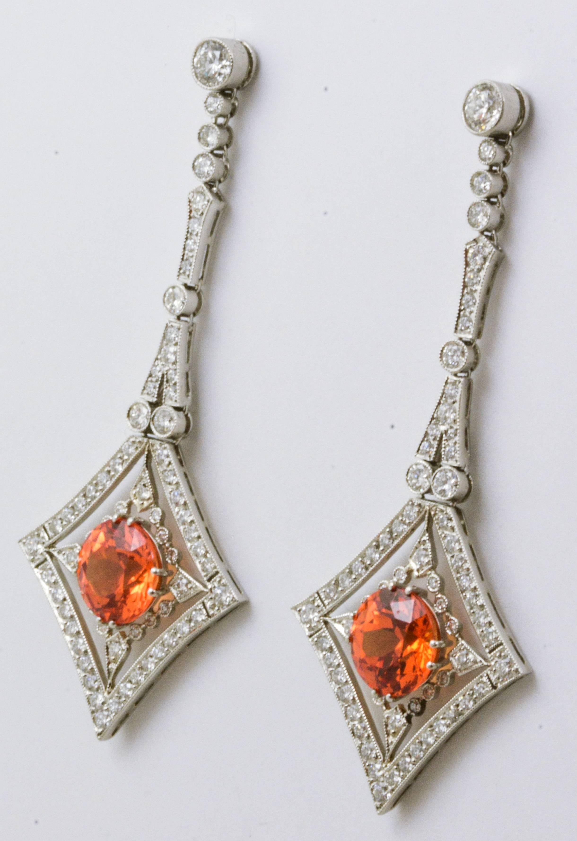 Wrapped in a fascinating combination of shimmering diamonds and platinum, are a pair of  round, custom, brilliant cut Mandarin Garnets (2.72 carats). She will look absolutely stunning and exquisitely dressed in these platinum drop earrings. They are