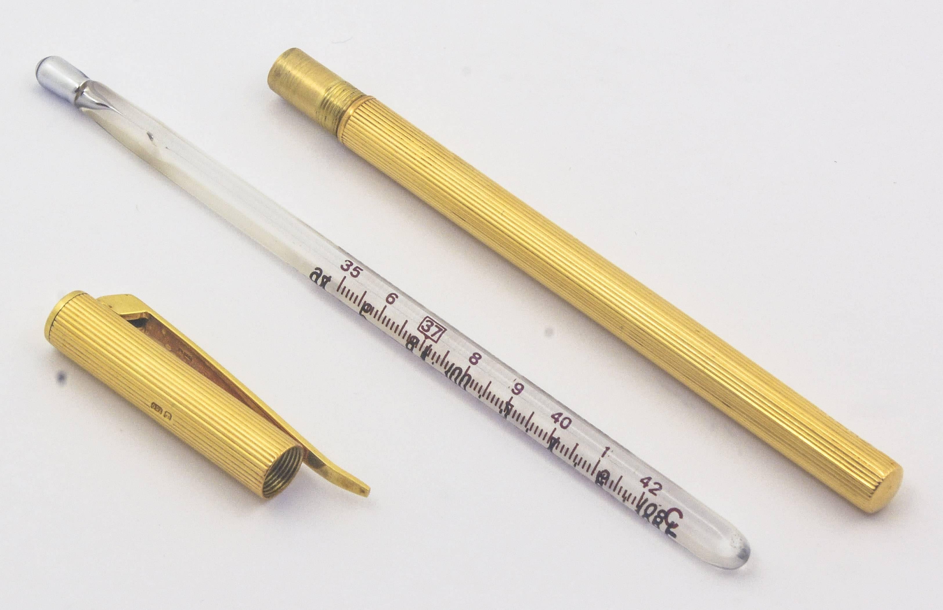 Sure to be an exciting conversation piece, this 18kt yellow gold thermometer case is fashioned with a pocket clip and artistic ribbing around the barrel. It comes with a mid-twentieth century style thermometer and measures 4.30in long and 6.4mm in