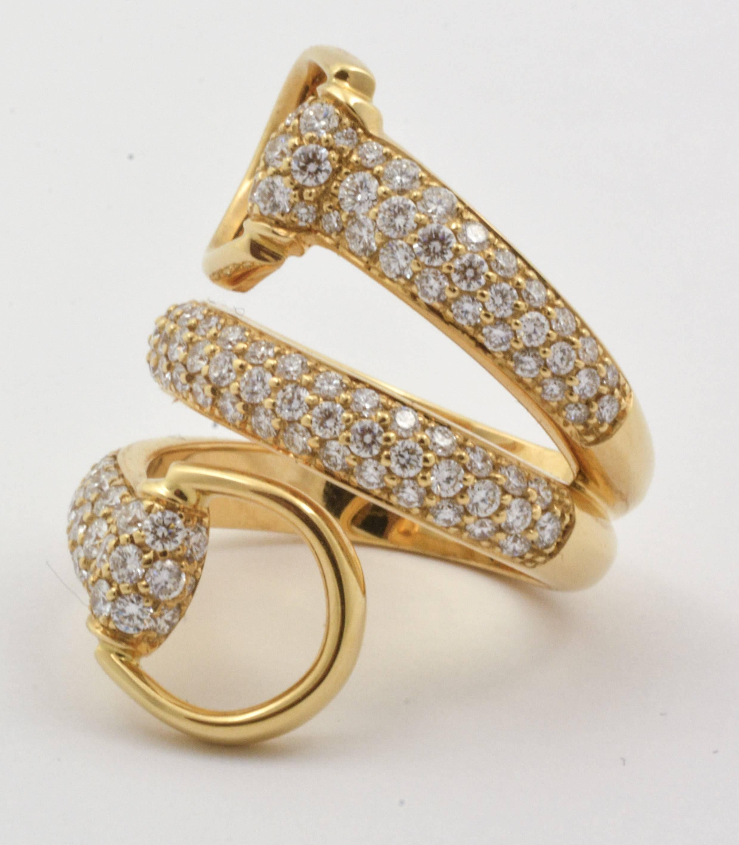 1.98 carats of round brilliant cut diamonds (clarity VS1 color G) wrap delicately around the finger in this gorgeous Gucci 18kt yellow gold horse bit contraire ring. Lovely loops of gold at either end of the ring give this Gucci diamond piece a