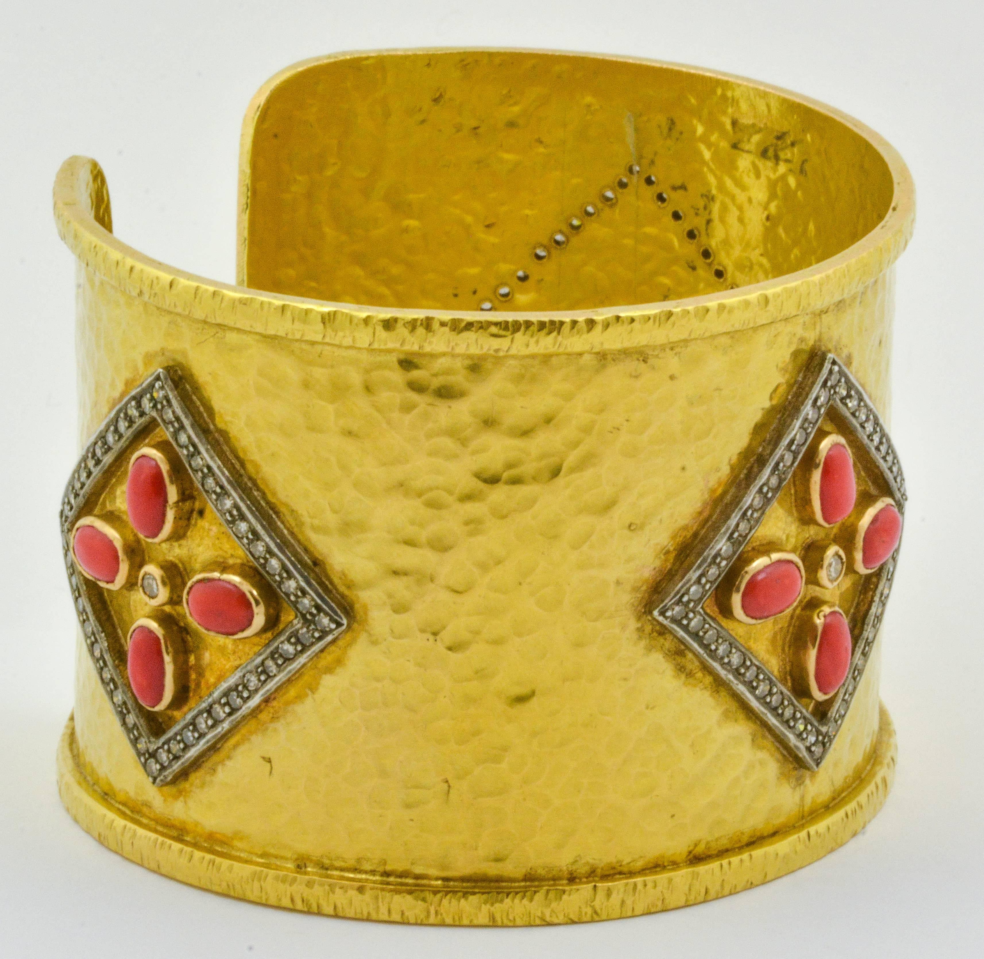 This strikingly beautiful 18kt yellow gold estate cuff bracelet features twelve oval-cut pieces of richly colored coral. They are set in groups of four framed by sterling silver diamond set halos. This unique masterpiece measures 40.44mm wide and
