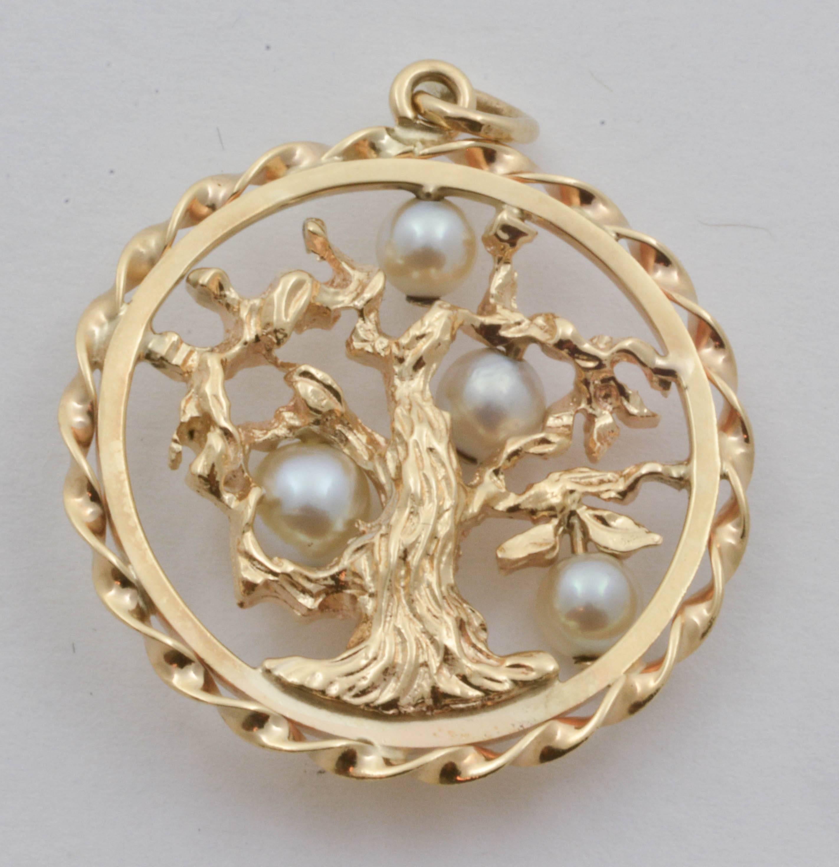 A beautifully artistic rendering of a gnarled tree is set in this pendant with four round cultured pearls. Fashioned from yellow gold and framed with both a flat band and a twisted ribbon border, this piece is a remarkably unique pendant that is