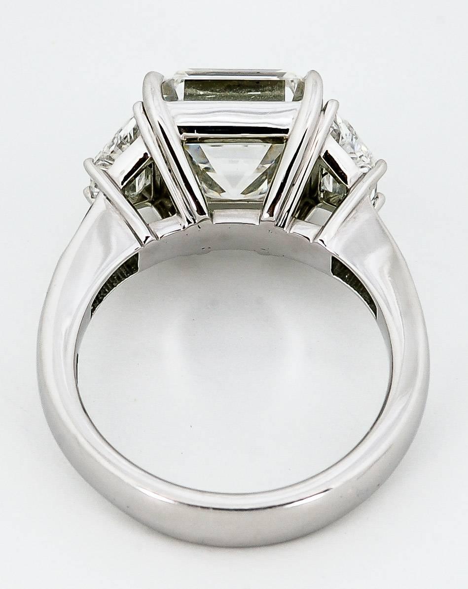 This enchanting platinum ring makes its magic with a 5.53 carat Asscher-cut diamond (clarity SI1 color H; GIA report 15210803). Two trapezoid cut diamonds weighing 0.95 carats total (clarity VS color G) and two tapered baguette cut diamonds weighing