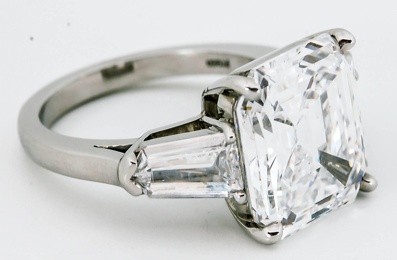 A dazzling 8.02 carat emerald cut diamond (clarity VS2 color D) is accented by two bullet cut diamonds weighing 1.33 carats total (clarity SI1 color D-E) in this lovely engagement ring that is sure to catch any eye.