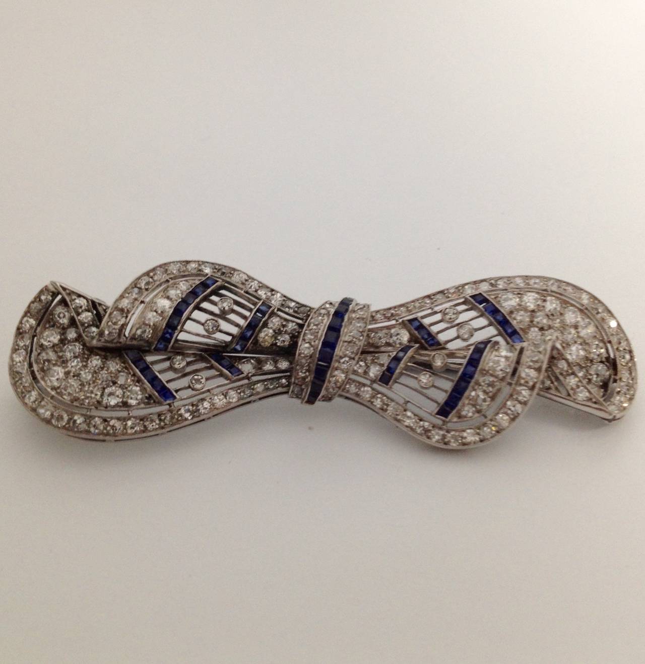 Art Deco Chic and Sophisticated Sapphire Diamond Platinum Lacy Bow Pin In Excellent Condition In New York, NY