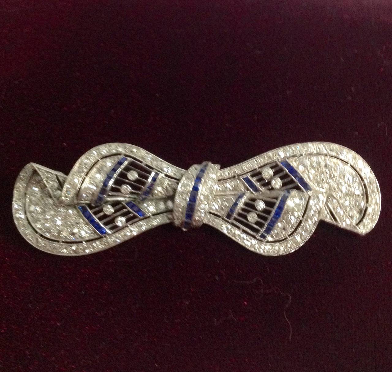 Platinum Sophiscated Figural Bow Brooch Consisting of numerous calibre cut beautiful color Sapphires embellished with numerous old European cut diamonds weighing approximately 3 carats and sapphires weighing approximately 1.50 cts designed wih