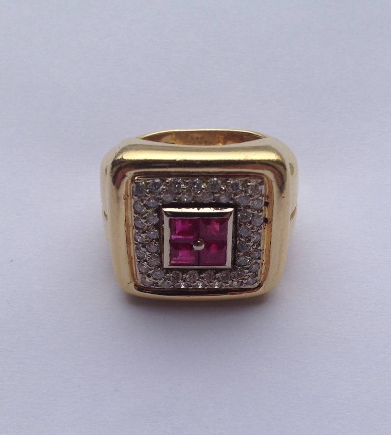 18kt Yellow Gold And Custom Cut Calibre Square Cut Ruby Unisex Ring Surrounded by numerous high quality full cut Diamonds in a square shape setting with beautiful seams design thruout ring