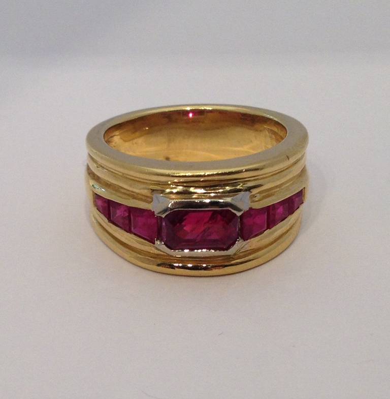 18kt yellow gold heavy band ring consisting of 7 custom cut handmade beautiful luscious color rubies weighing approximately 1.20 carats total weight & centering a rectangular cut ruby weighing approximately .60 ct beautifully designed with handmade