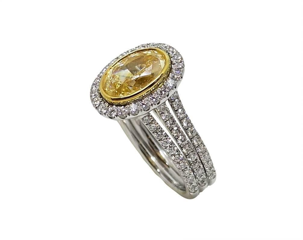Platinum and 18K Yellow Gold Ring With Center Oval Cut Yellow Diamond Weighing A Total Carat Weight Of 3.01 Carats Fancy Light Yellow Color and VS2 Clarity (GIA Report). Mounting has White Diamonds Surround the Center Stone and Cover The Shank and