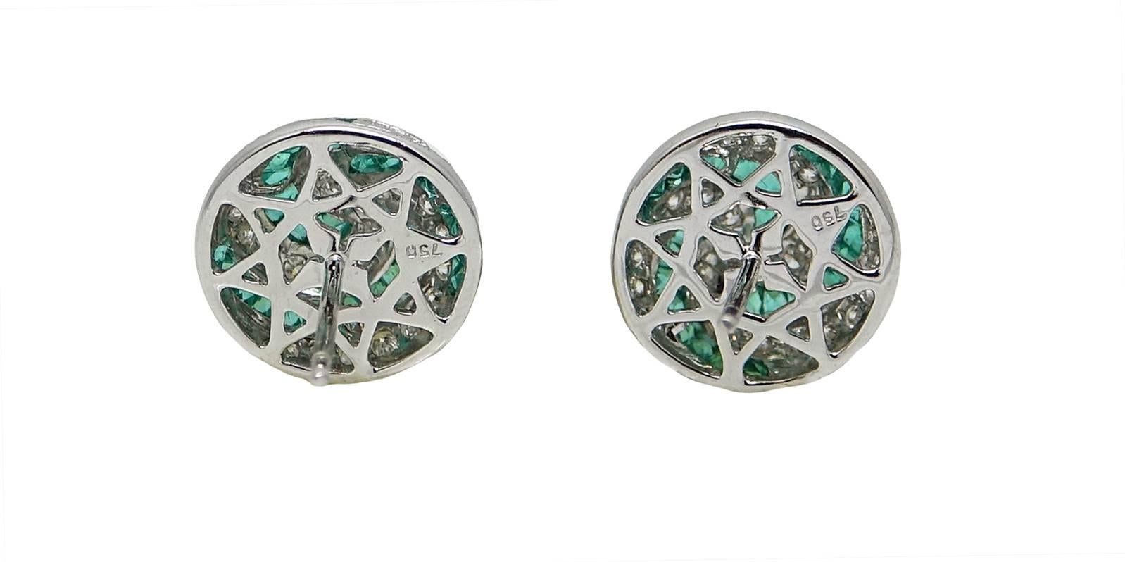 18K White Gold Stud Earrings With A Swirl Design Of Round Cut Diamonds Weighing A Total Carat Weight Of 0.99 Carats and Calibre Cut Emeralds Weighing A Total Carat Weight Of 2.45 Carats.