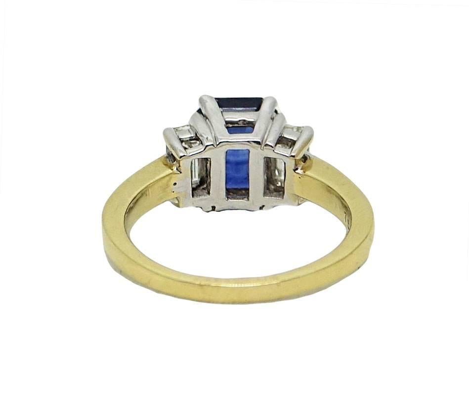 This 18K Yellow and White Gold Ring With Center Emerald Cut Sapphire Weighing A Total Carat Weight Of 2.15 Carats and Two Side Emerald Cut Diamonds With A Total Carat Weight Of .60 CaratsJ Color and VS Clarity. This Ring Is A Size 6.5