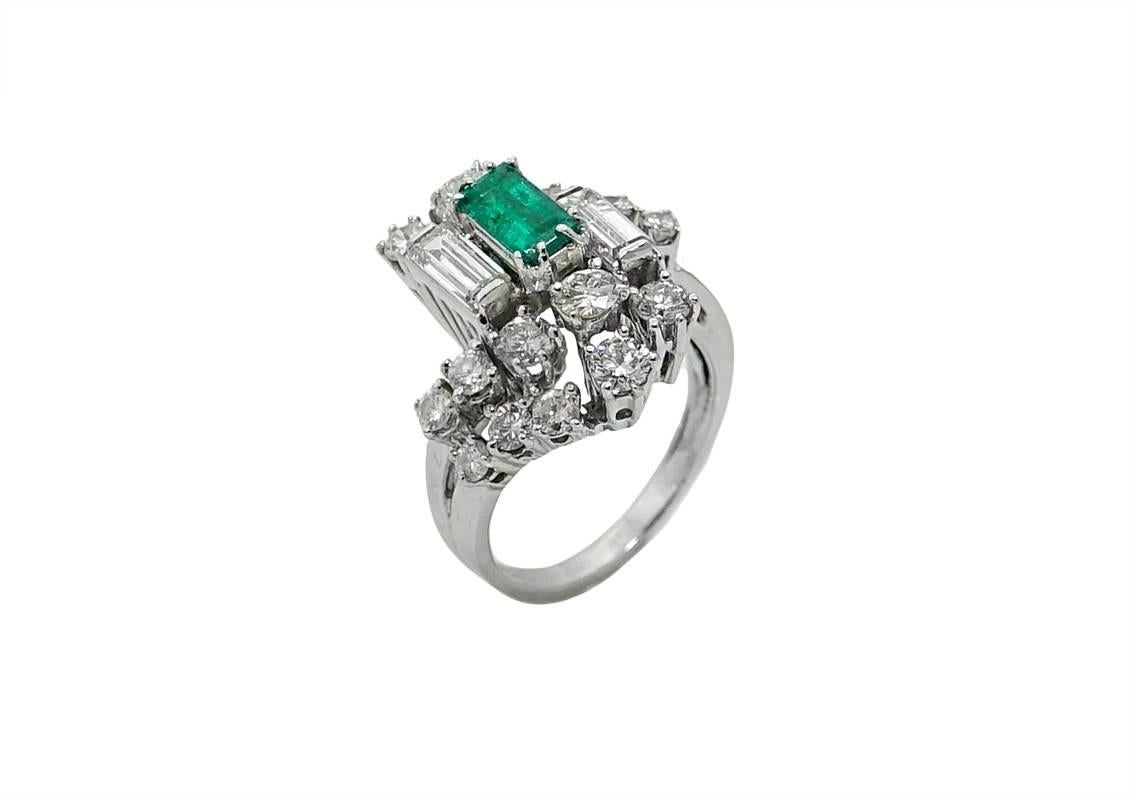 This 18K White Gold Ring Has An Emerald Cut Colombian Emerald In The Center Weighing A Total Carat Weight Of .75 Carats and Diamonds Weighing A Total Carat Weight Of 3.00 Carats. This Ring Is A Size 6.5.