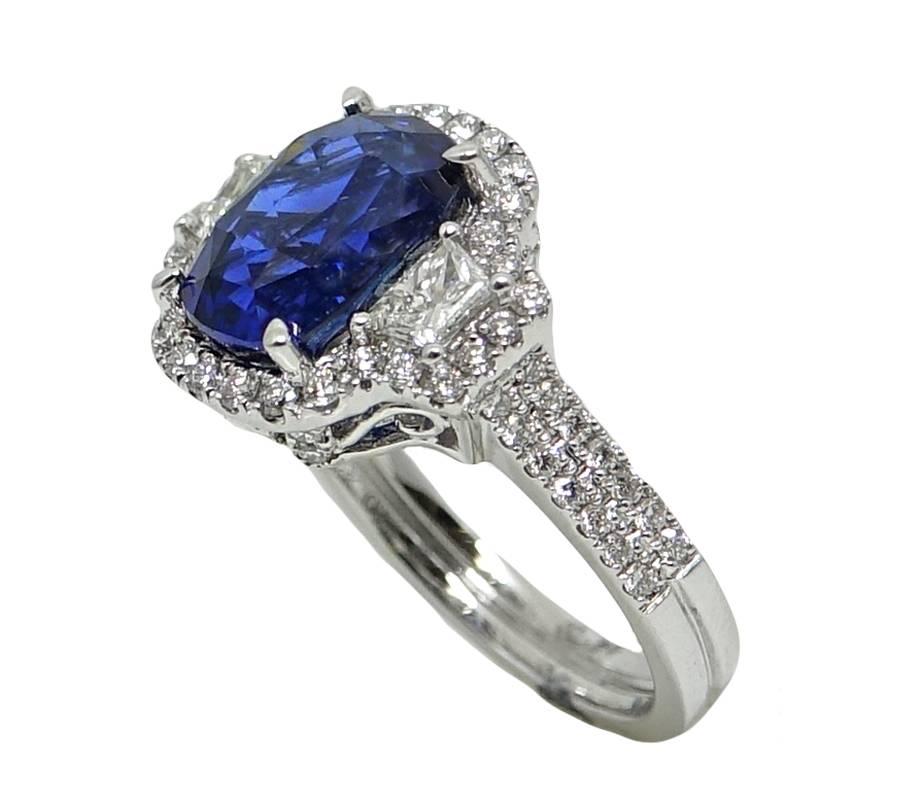 18K White Gold Ring With A Center Cushion Cut Sapphire Weighing A Total Carat Weight Of 4.92 Carats, and Diamonds Surrounding The Sapphire and Shank Weighing A Total Carat Weight Of .98 Carats. This Beautiful Ring Is A Size 6.5 and Can Be Sized Upon