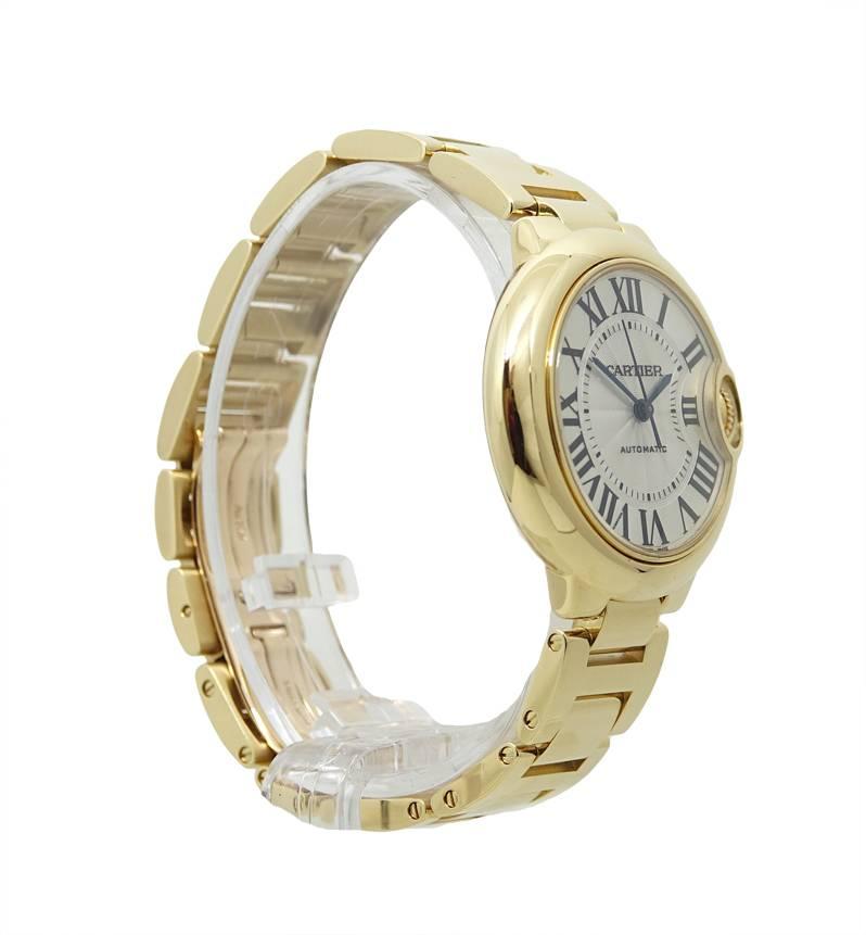 This Elegant 18K Yellow Gold Ballon Bleu Cartier Watch Is A Size 33mm, and 9.96mm Thick With A Fluted 18K Yellow Gold Crown With A Blue Cabochon Shaped Sapphire. This Cartier Watch Has An 18K Yellow Gold Bezel, A Silver Dial With Roman Numerals Dial