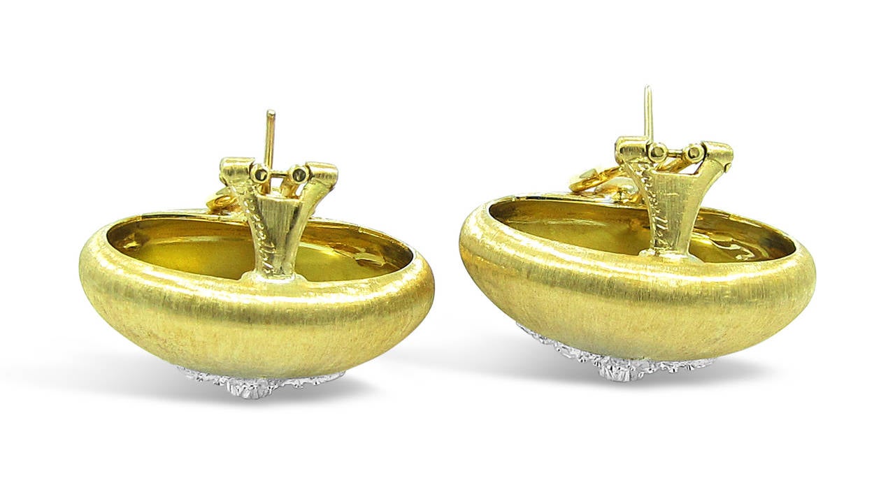 These beautiful Estate Buccellati Button earrings are from the Classica Collection. The 18k yellow gold hand brushed earrings have a star center made of 18k white gold centered by an approximate .07ct round brilliant diamond. This pair of earrings