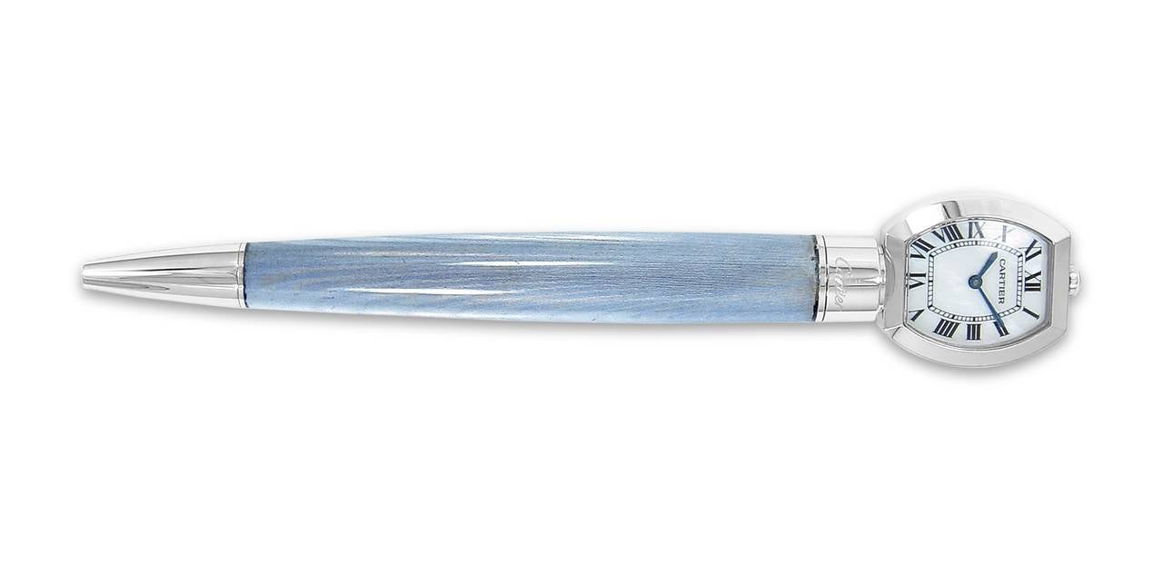 This beautiful Ballpoint pen has an iridescent white lacquer and platinum finished details.
 On top of this pen is a Tonneau quartz watch with mother of pearl dial and black markers with metallic blue hands. In working condition. 
This pen is