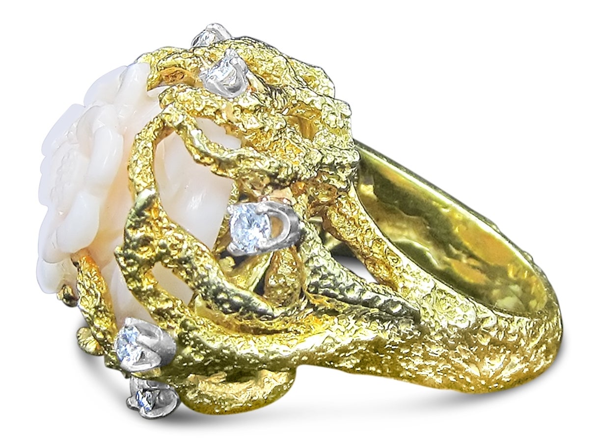 We are pleased to offer this beautiful ring with a coral piece carved into a flower bloom with diamonds set in 18k yellow gold. 8 round diamonds weigh approximately .75 total carats. Center carved coral is set in a coral designed yellow gold