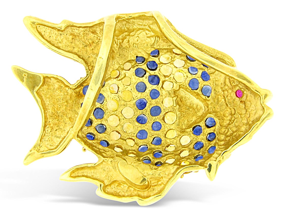 This colorful pendant is made of 18K yellow gold with 12.50cts of blue and yellow sapphires, and a ruby eye. This fish weighs a 34.67 grams, and is 2.1
