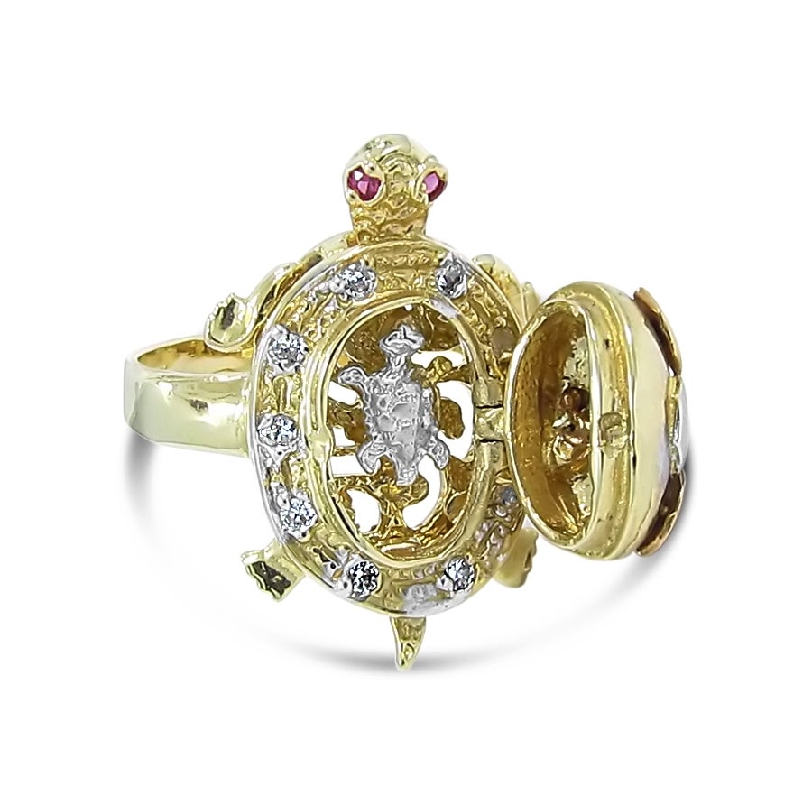 This is a very neat statement piece. The tri-color 14k gold turtle ring has a shell that opens up to a baby turtle on the inside. This is a solid piece which the head feet and tail do not swivel. There are 10 .02ct round old cut diamonds with 2 ruby