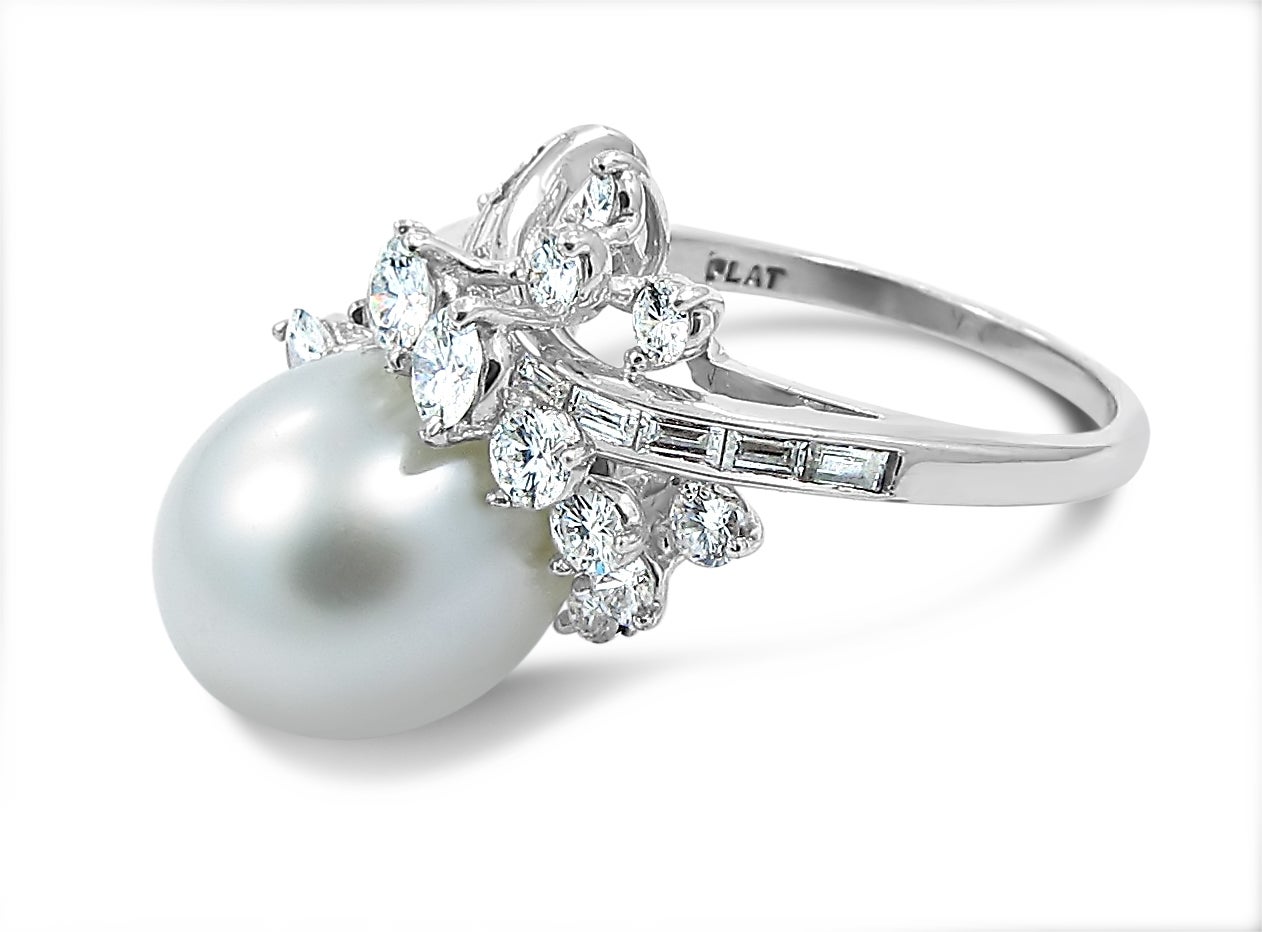 South Sea Cultured Pearl has a beautiful white luster. It is oval shaped and measures approximately 14 x 11.50mm. There is a mix of round and baguette diamonds with graduating sizes which equal an estimated weight of 2.25ctw. Pearl and diamonds are