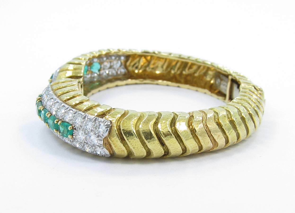 This is definitely one of those bracelets that you wont see another of. It is a beautiful David Webb design. This bangle bracelet is created with 18k yellow gold with a wave design. There are 10 absolutely beautiful oval emeralds that measure on