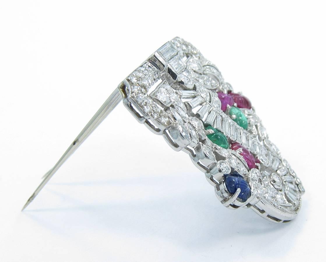 This Art Deco Brooch has beautiful diamonds of baguette and round with great color and clarity all securely set in platinum. There are 3 rubies, 2 emeralds and a sapphire that have been fancy cut and carved to look like leaves. Very impressive