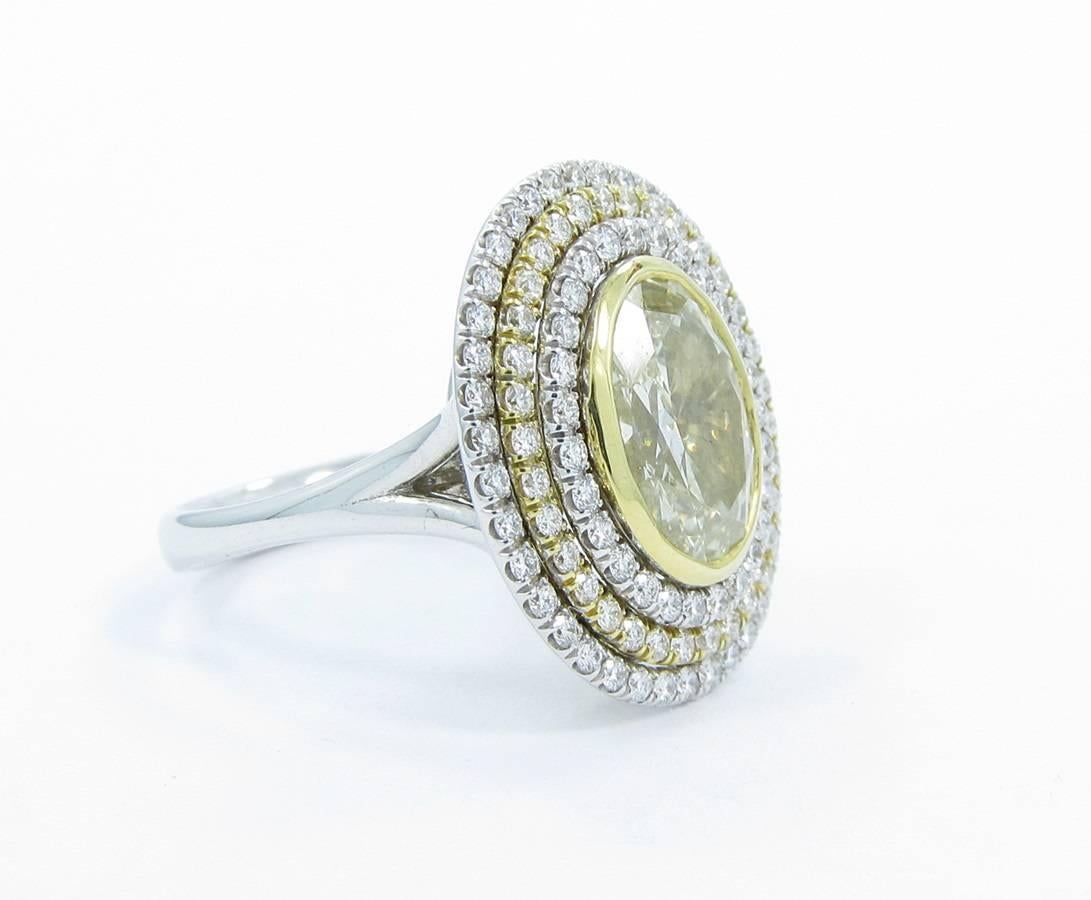 This beautiful ring holds 4.15cts tw of diamonds. Center fancy yellow diamond weighs 3.12cts with clarity of SI and securely bezel set in the 18k yellow gold. The triple halo holds 1.03cts of round brilliant cut diamonds all securely prong set in