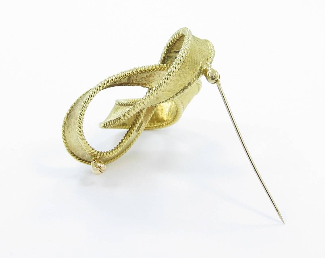 This large Craig Drake Ribbon brooch is created in 18k yellow gold. This brooch has an outside diameter at its widest of 1.75